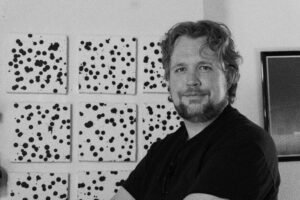 Kevin standing in from of a 3x3 panel of abstract circles